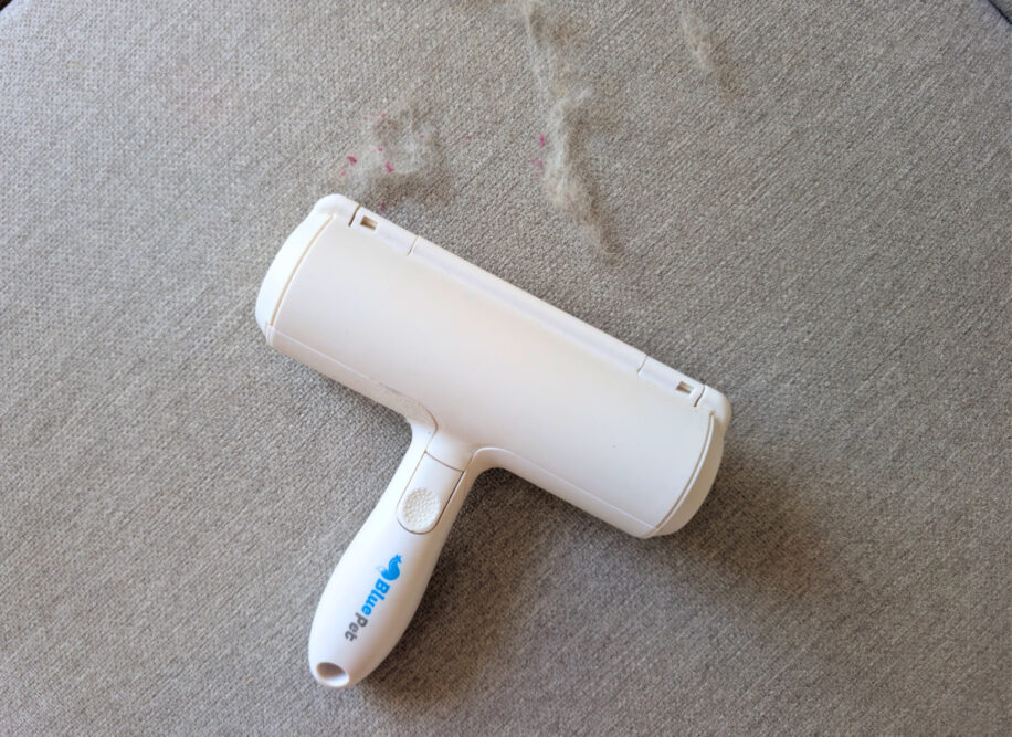 BluePet RolloTollo Tierhaarentferner auf grauem Sofa neben aufgenommenen Tierhaaren