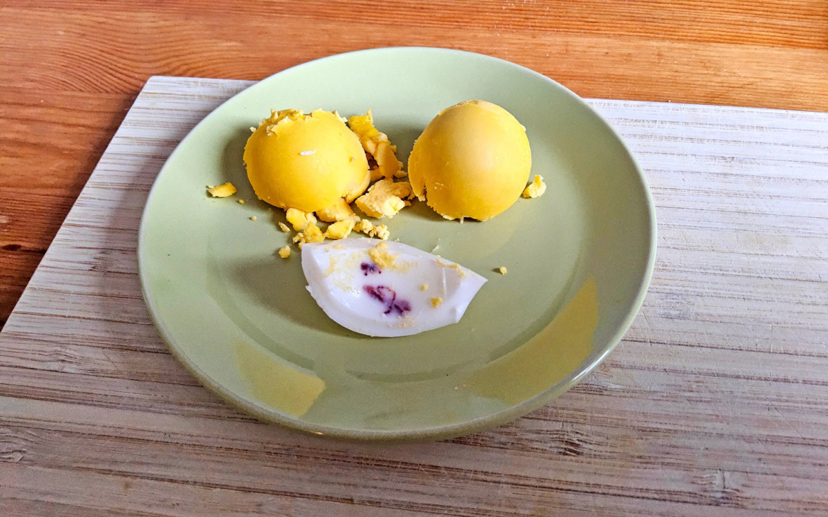 Brauner Fleck im Ei: Aufgeschnittenes Ei auf einem grünen Teller, im Eiweiß ist ein rötlich-brauner Fleck zu sehen.