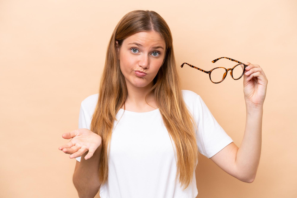 Frau mit fragendem Blick hält Brille in der Hand
