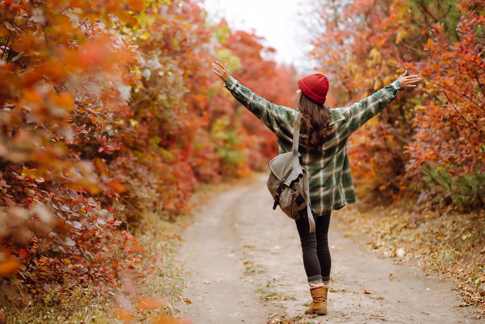 Frau tanzt mit ausgestreckten Armen im Wald im Herbst