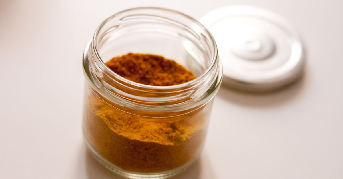 Close-up of a glass jar filled with yellow spice powder on a white background, highlighting zero waste storage.