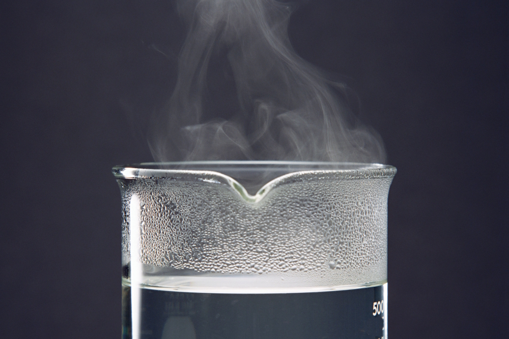 Dampfendes Wasser in einem Becherglas als Ausgangspunkt für die Gewinnung von destilliertem Wasser.