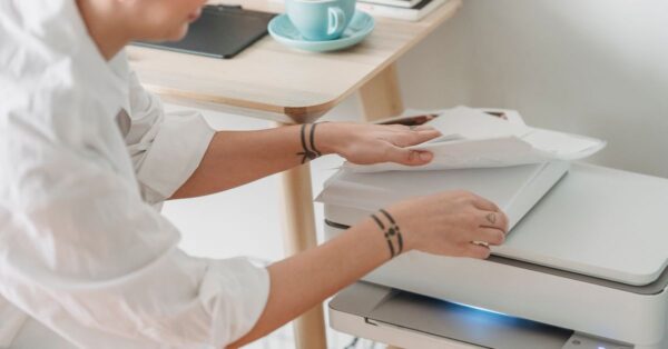 Frau nimmt mehrere eingezogene Blätter aus einem Drucker