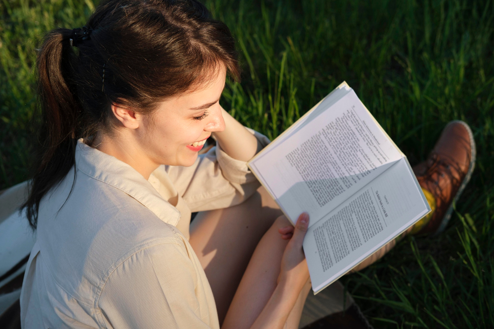 Auszeit vom Alltag: Junge Frau sitzt beim Lesen eines Buches im Grünen