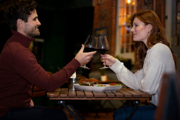 Mann und Frau stoßen bei einem gemeinsamen Restaurantbesuch mit Rotwein an