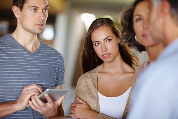 Vier Personen führen ein Gespräch über ein schwieriges Thema in der Familie, eine Frau blickt nachdenklich.