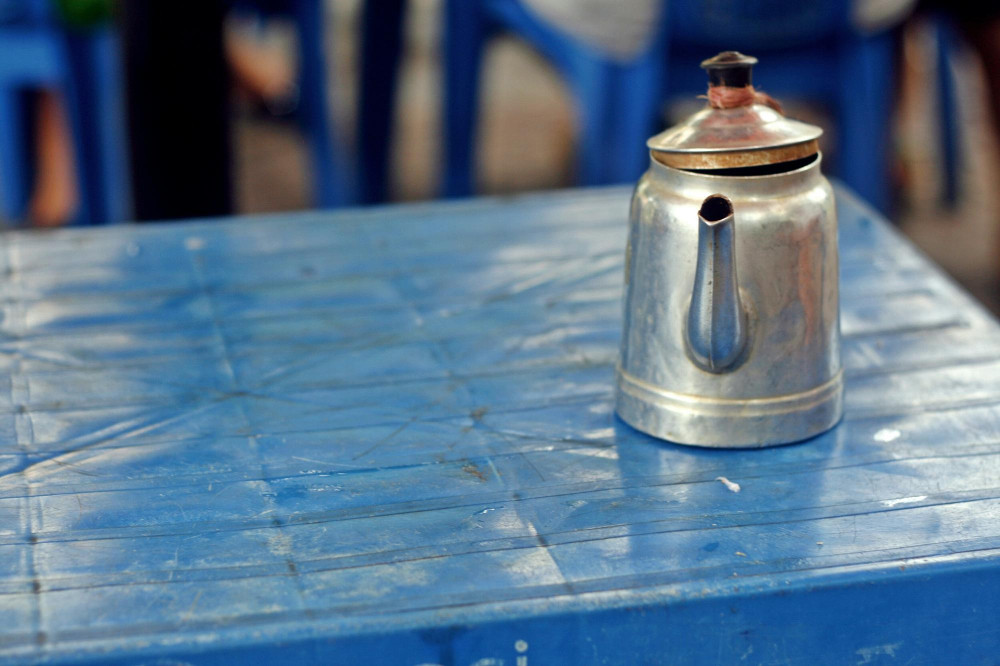 Abgenutzte, abgeplatzte blaue Tischoberfläche mit altem Metallkännchen - Symbolfoto zu „Farbe von einem Holztisch entfernen“, abblätternde Farbe und Renovieren im DIY-Kontext.