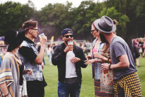 Junge Leute unterhalten sich mit Bier in der Hand auf Festival – Überlebenstipps