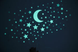 Phosphoreszierende Glow-in-the-Dark Sterne und Mond an der Wand - anschauliches Beispiel für fluoreszierende Farbe vs. phosphoreszierend im Dunkeln.