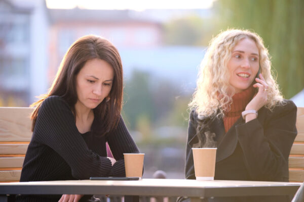 Zwei Frauen sitzen im Café, eine wirkt nachdenklich – Symbolbild für ein schwieriges Gespräch mit einer Freundin über ihren Partner.