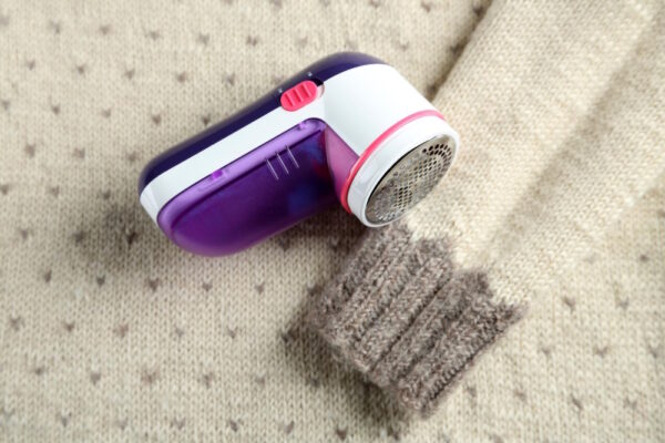 Fusselrasierer auf einem gestrickten Pullover mit sichtbarem Pilling