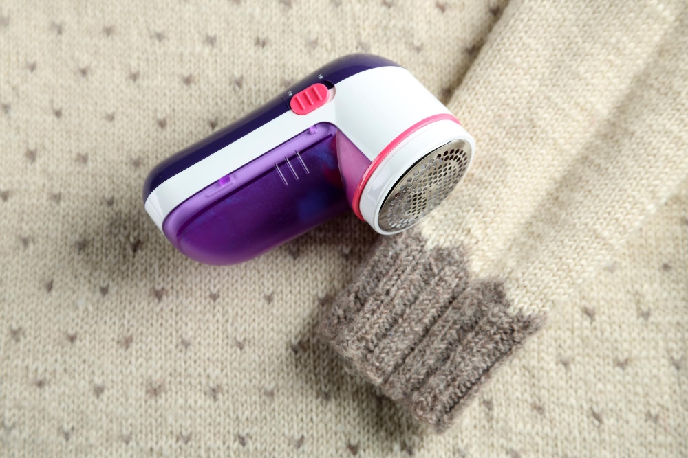 Fusselrasierer auf einem gestrickten Pullover mit sichtbarem Pilling