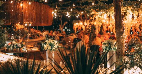 A beautifully lit outdoor setting with hanging lights and floral decor, perfect for social gatherings.