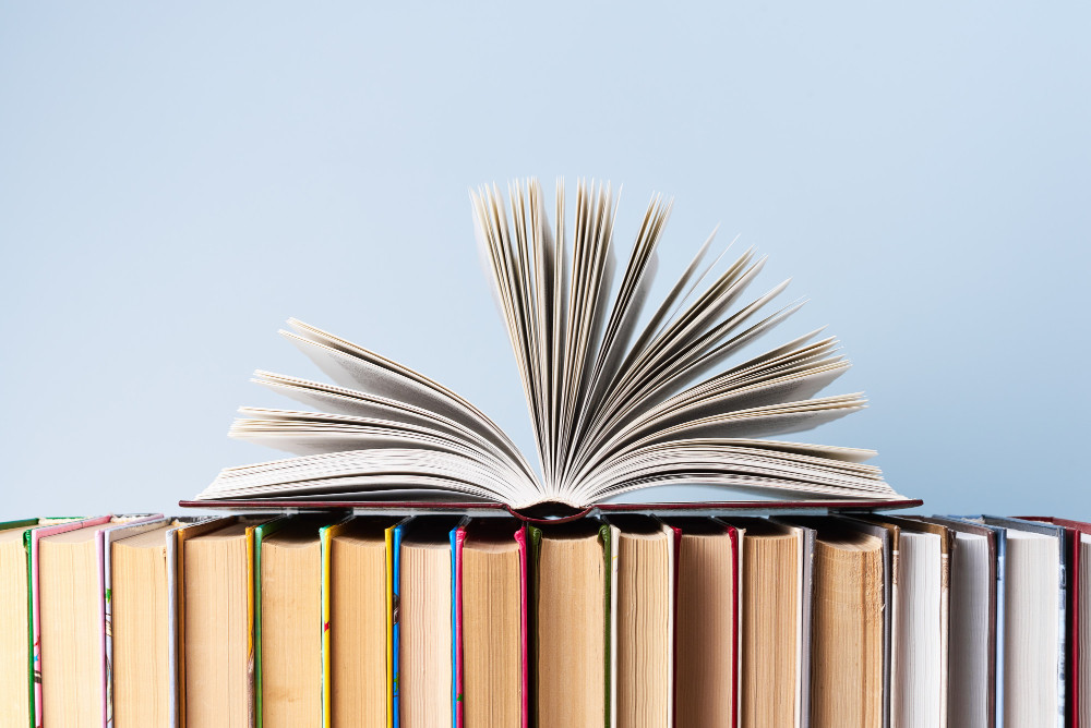 Gerüche aus Büchern entfernen: Aufgeschlagenes Buch steht auf einer Reihe alter Bücher, passend zu muffigem Dachboden- oder Kellergeruch.