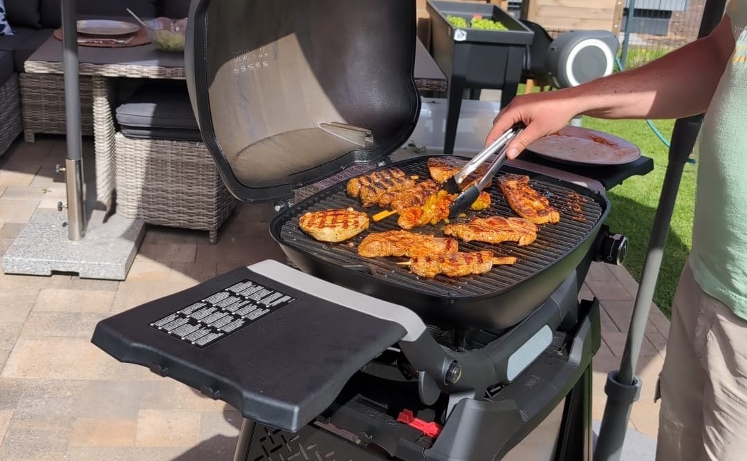 Gasgrill vorheizen und Grillgut auf heißem Rost im Garten wenden