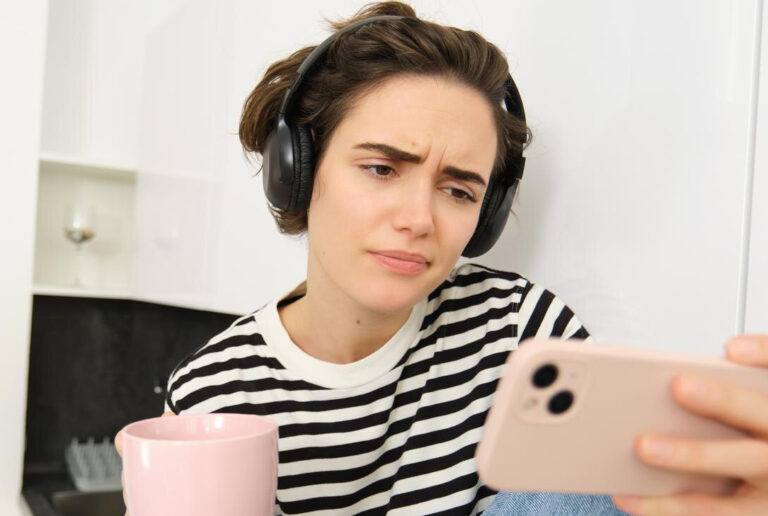 Frau hält ihr Smartphone quer und schaut irritiert auf den Bildschirm