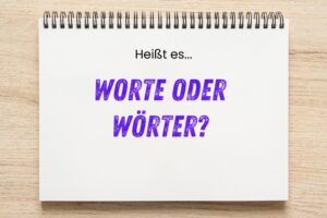 Notizblock mit der Aufschrift „Heißt es… WORTE ODER WÖRTER?“ in schwarzer und lila Schrift auf hellem Holztisch.