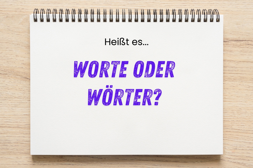 Notizblock mit der Aufschrift „Heißt es… WORTE ODER WÖRTER?“ in schwarzer und lila Schrift auf hellem Holztisch.