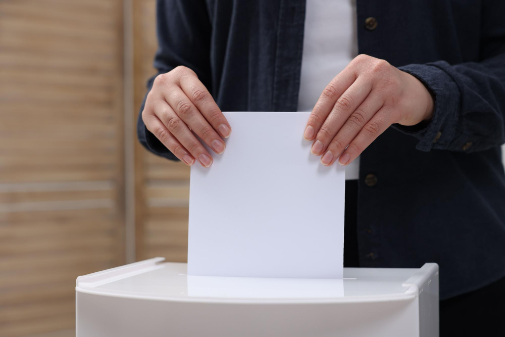 Ist es sinnvoll, kleine Parteien zu wählen: Eine Person hält einen Wahlzettel und steckt ihn in eine Wahlurne, symbolisch für die Entscheidung bei der Stimmabgabe.