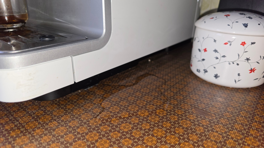 Wasserpfütze unter einer Kaffeemaschine auf der Küchenarbeitsplatte