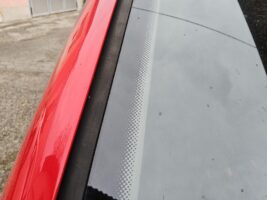 Rote Autosäule neben Windschutzscheibe mit typischen schwarzen Siebpunkten am Rand.