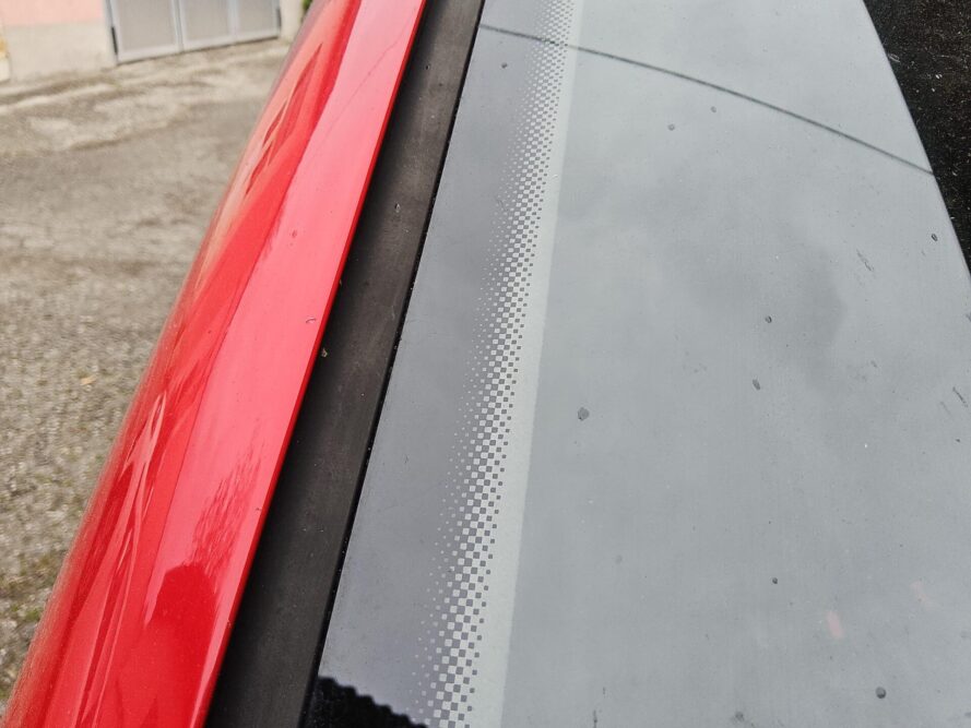 Rote Autosäule neben Windschutzscheibe mit typischen schwarzen Siebpunkten am Rand.