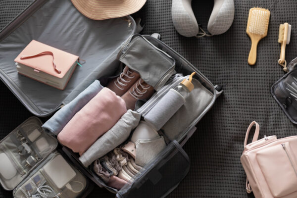 Geöffneter Koffer mit knitterfreier sorgfältig gerollter Kleidung und Reiseutensilien
