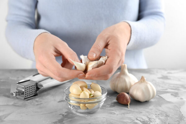 Großaufnahme von Händen, die Knoblauch schälen.