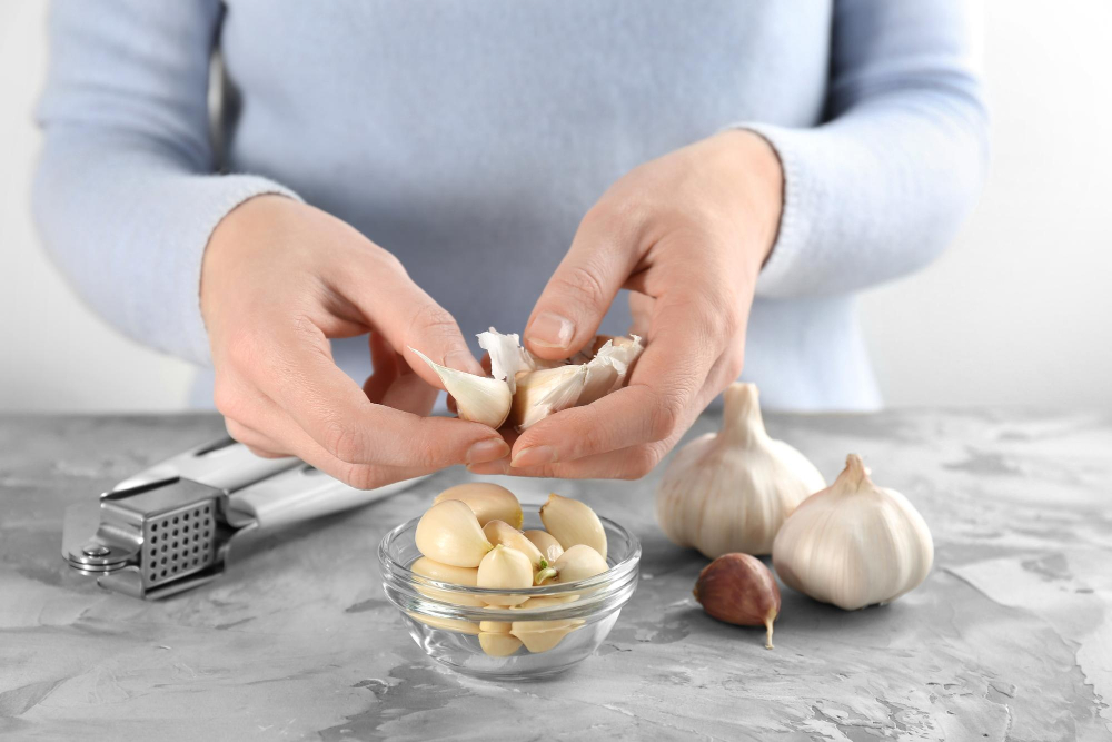 Großaufnahme von Händen, die Knoblauch schälen.