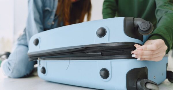 Person öffnet einen hellblauen Hartschalenkoffer