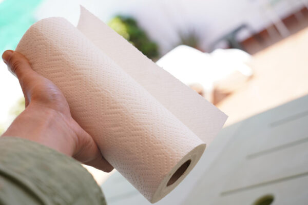 Hand hält eine Küchenpapierrolle, Blatt halb abgerissen - symbolisch für den Umstieg auf wiederverwendbare Alternativen.