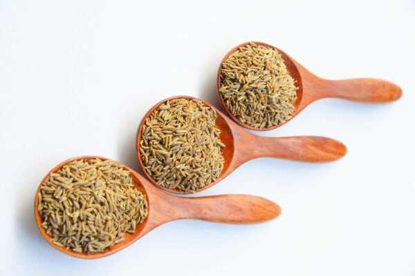 Drei Holzlöffel mit Kümmelsamen auf hellem Hintergrund