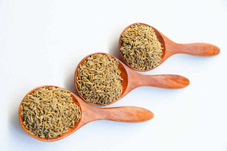 Drei Holzlöffel mit Kümmelsamen auf hellem Hintergrund