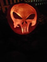 Geschnitzter Kürbis mit Punisher-Logo, klaren Lichtkanten und dunklem Hintergrund