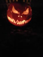 Gruselig geschnitzter Halloween-Kürbis mit bösem Blick, breitem Maul und leuchtendem Gesicht