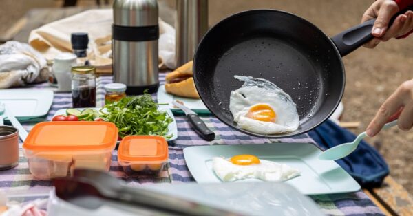 Spiegeleier und Lebensmittel auf einem Campingtisch im Freien
