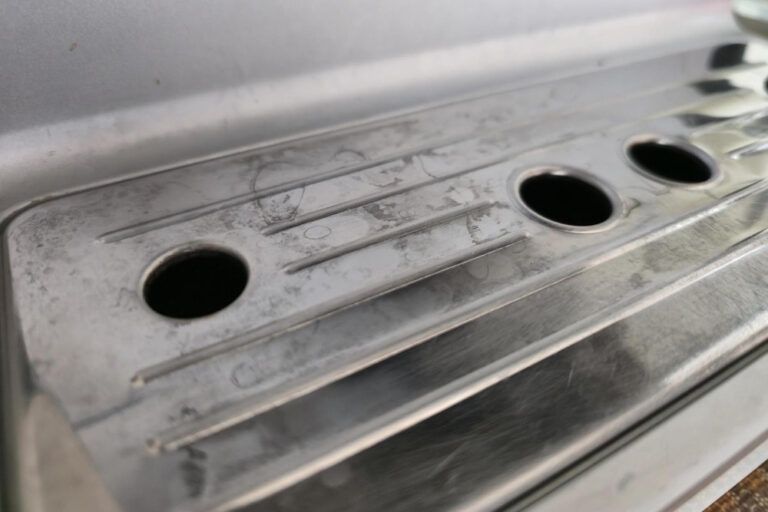 Matte Flecken auf Edelstahl an der Tropfschale einer Kaffeemaschine vor der Reinigung