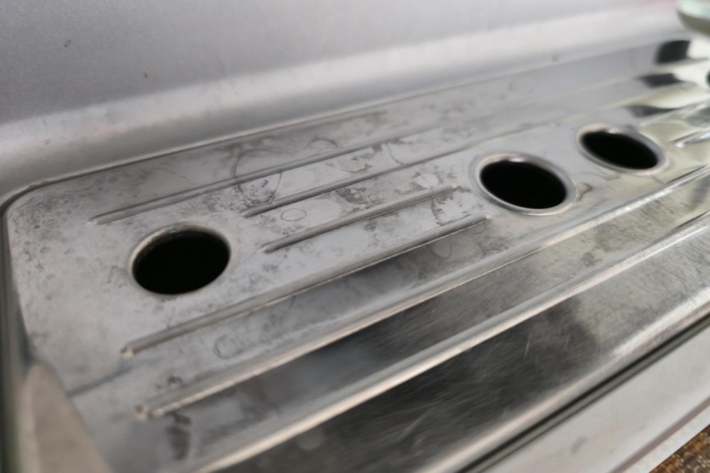 Matte Flecken auf Edelstahl an der Tropfschale einer Kaffeemaschine vor der Reinigung