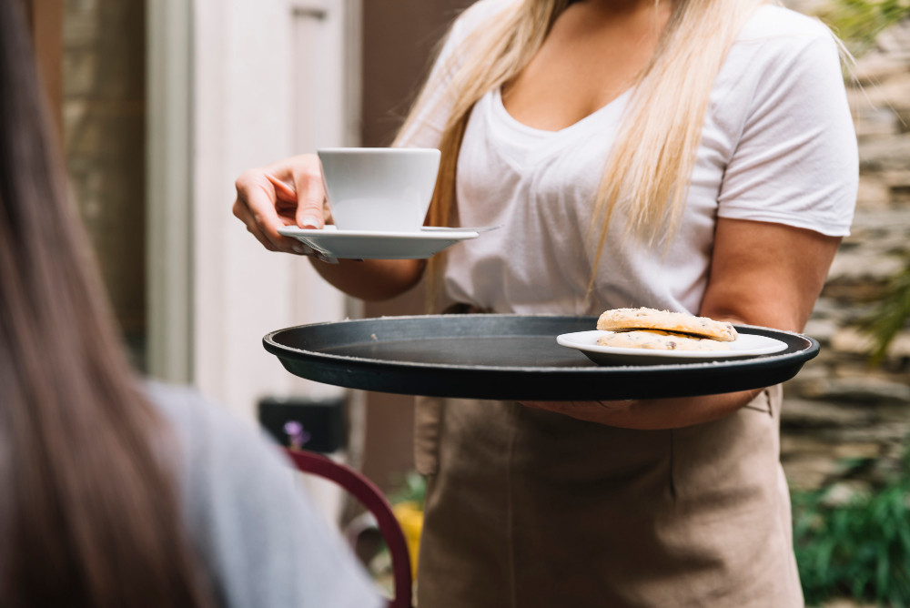 Kellnerin serviert eine Bestellung in einem Café als Symbolbild für einen Minijob