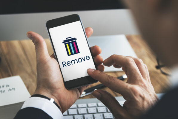 Eine Hand hält ein Smartphone mit Papierkorb-Symbol und der Aufschrift „Remove“, während ein Finger den Bildschirm berührt.