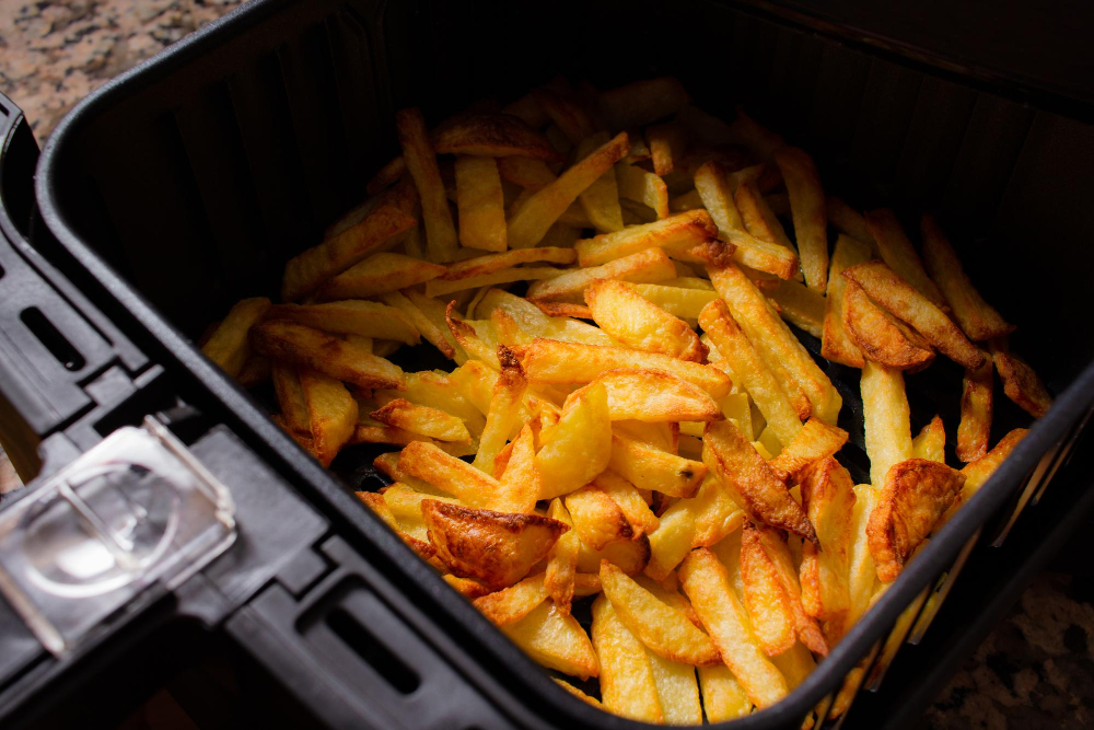 Frisch gebackene Pommes Frites in einer geöffneten Heißluftfritteuse
