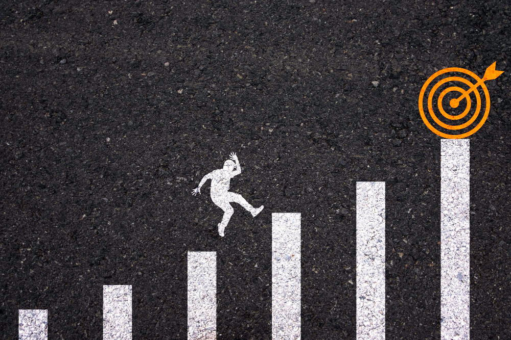 Grafik mit weißer Strichmännchen-Figur, die eine Treppe aus Balken hinauf auf ein orangefarbenes Ziel mit Pfeil zuläuft - Symbol für Schritte zu realistischen Zielen.