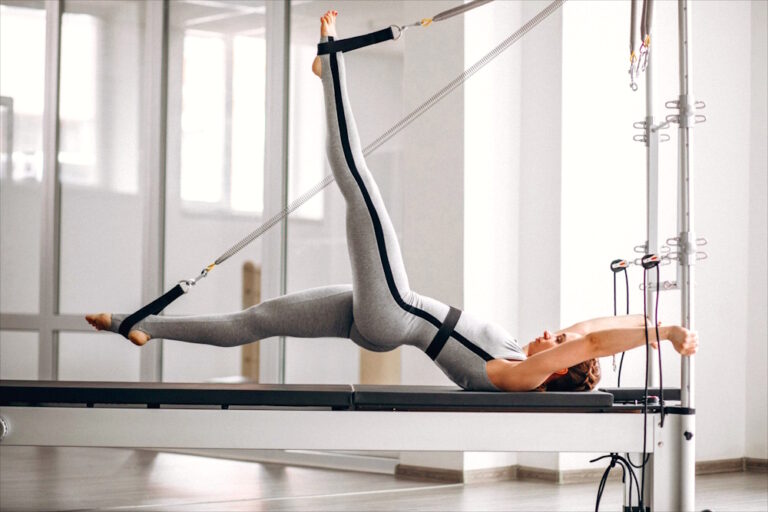Eine junge Frau macht Übungen an einem Pilates Reformer