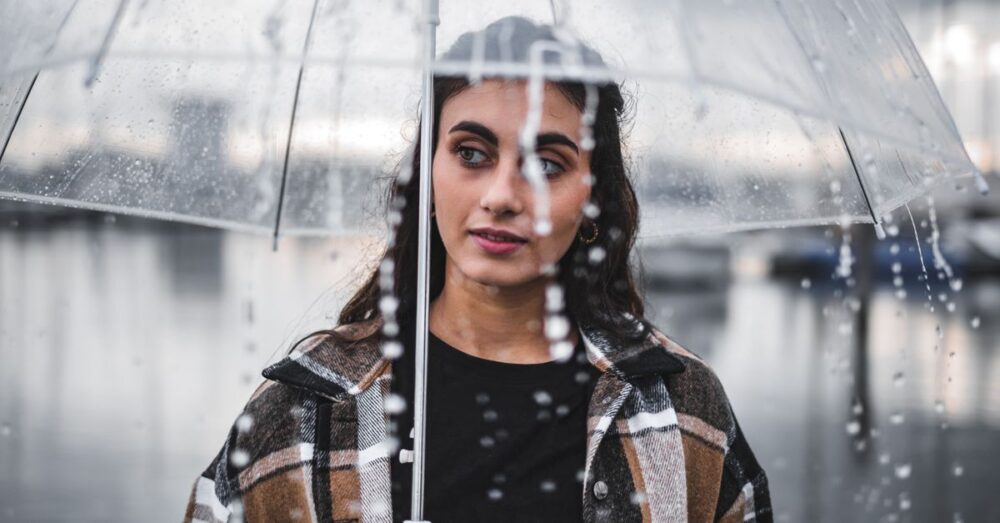 Frau hält an einem Regentag einen transparenten Regenschirm im Regen