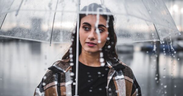 Frau hält an einem Regentag einen transparenten Regenschirm im Regen