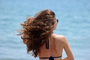 Rückenansicht einer Frau mit wehendem Haar am Meer - natürlicher Beach-Waves-Look