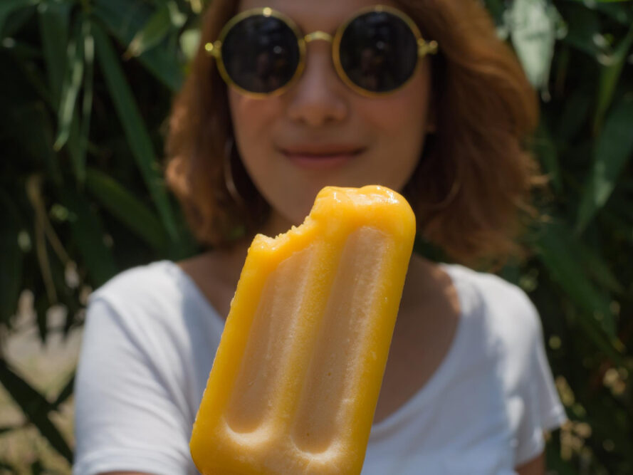 Frau mit Sonnenbrille zeigt ein selber gemachtes Wassereis in die Kamera.