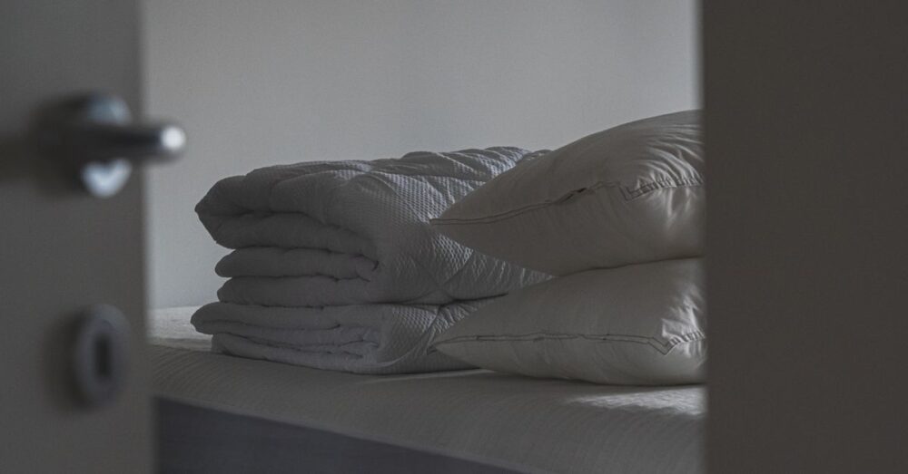 Gefaltete Sommerbettdecke und Kissen liegen ordentlich auf einem Bett im Schlafzimmer