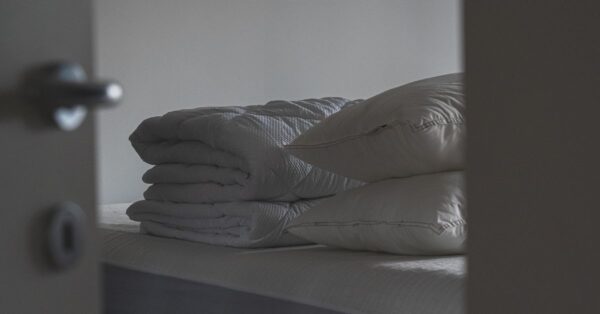 Gefaltete Sommerbettdecke und Kissen liegen ordentlich auf einem Bett im Schlafzimmer