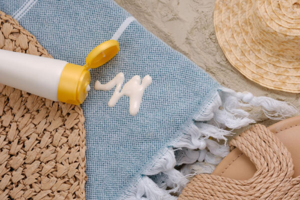 Sonnencreme auf blauem Stoff mit Sommeraccessoires